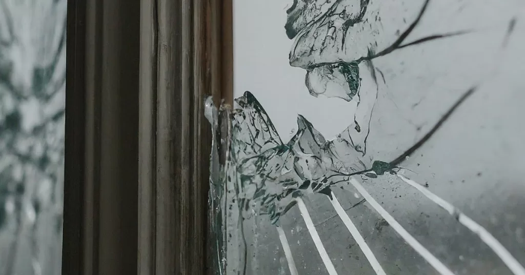 Weatherproofing Your Home Essential Tips for Glass Maintenance A close-up of a cracked window pane during a hurricane, with rain and wind blowing through the cracks.